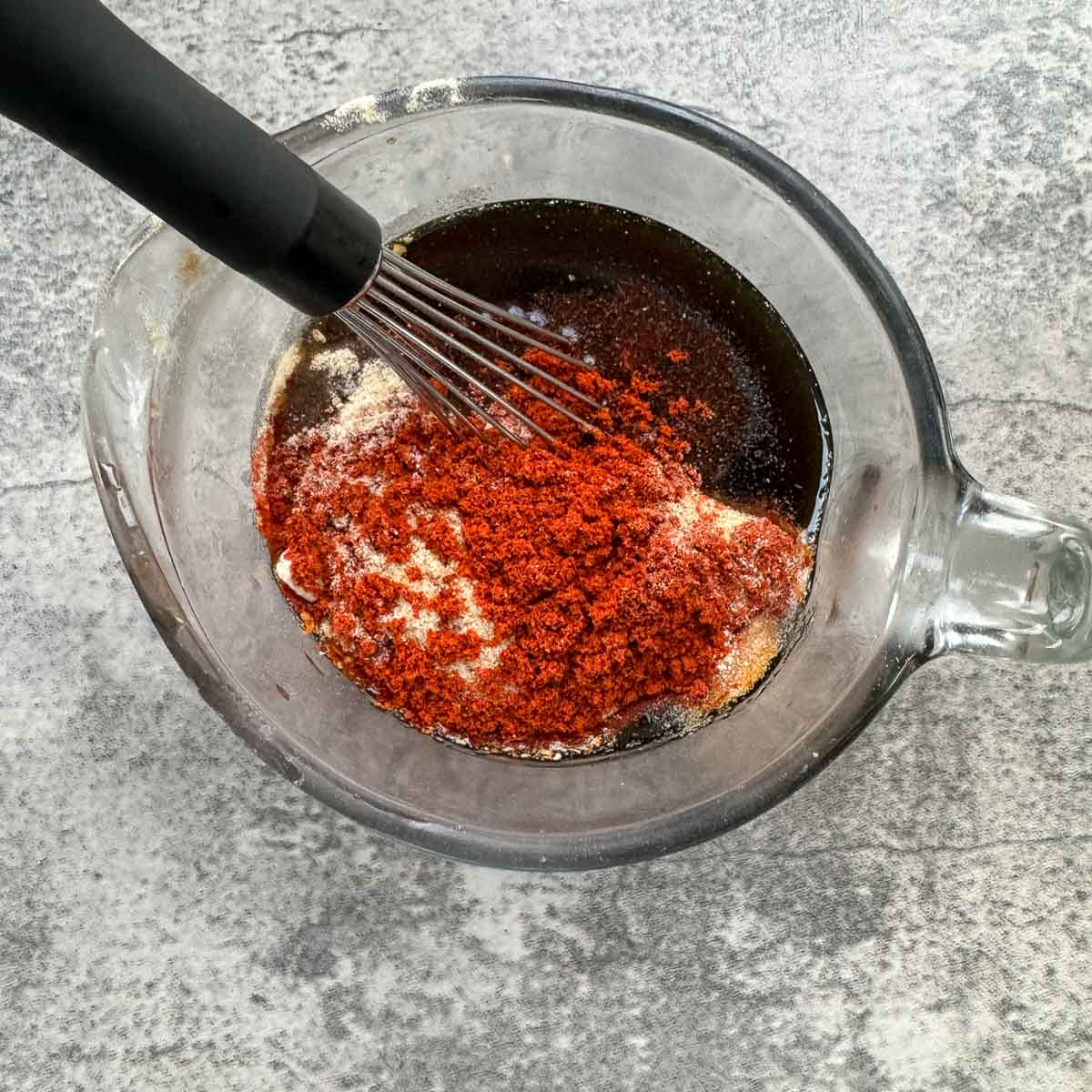 marinade ingredients in a measuring jar with a whisk.