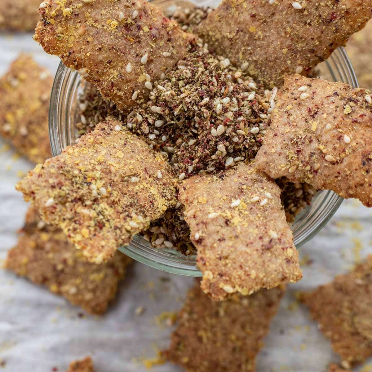 za'atar sourdough discard crackers in a bowl with more crackers around it.