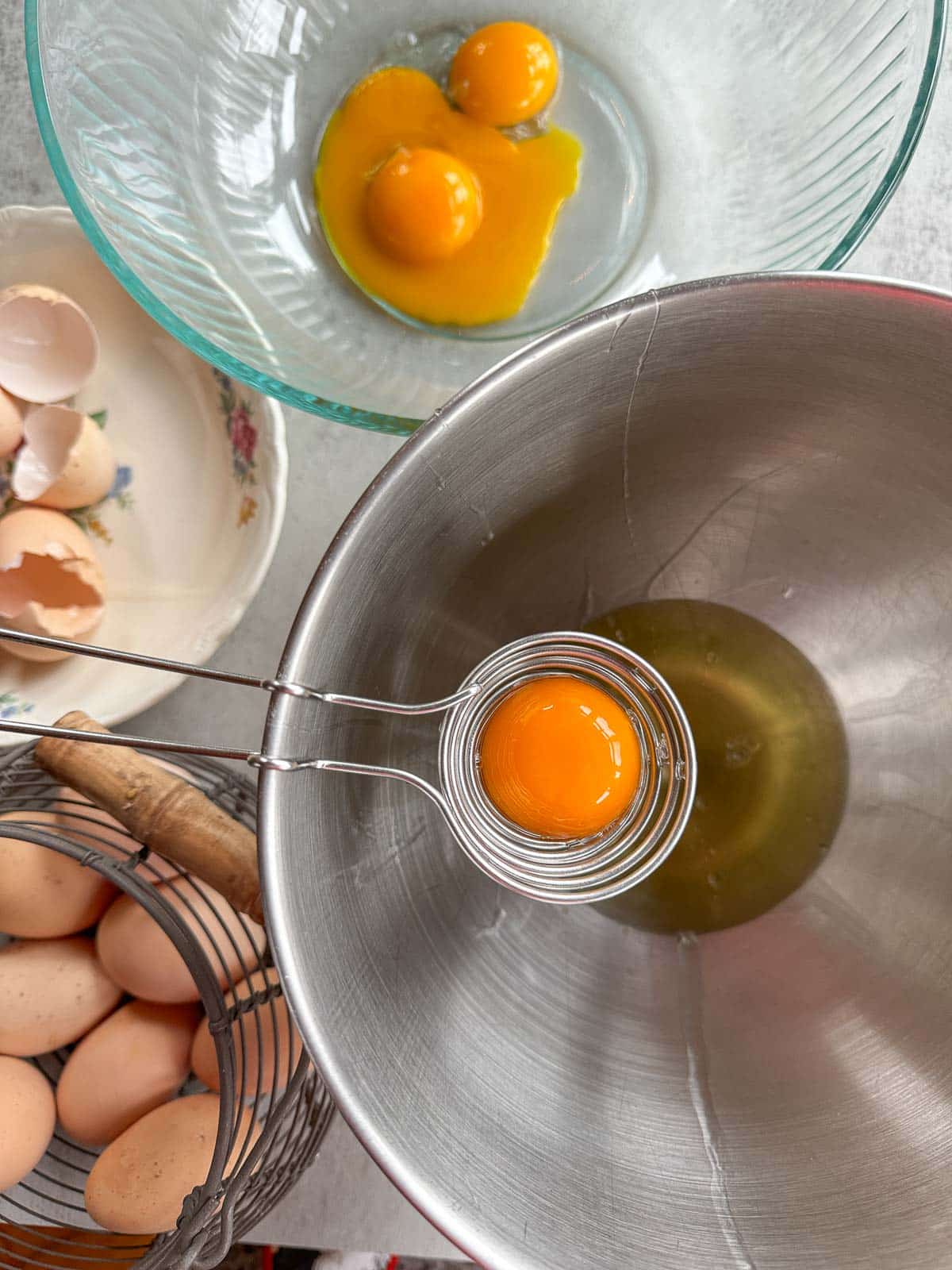 egg yolks being separated in a mixer bowl with ore eggs and egg shells around it.