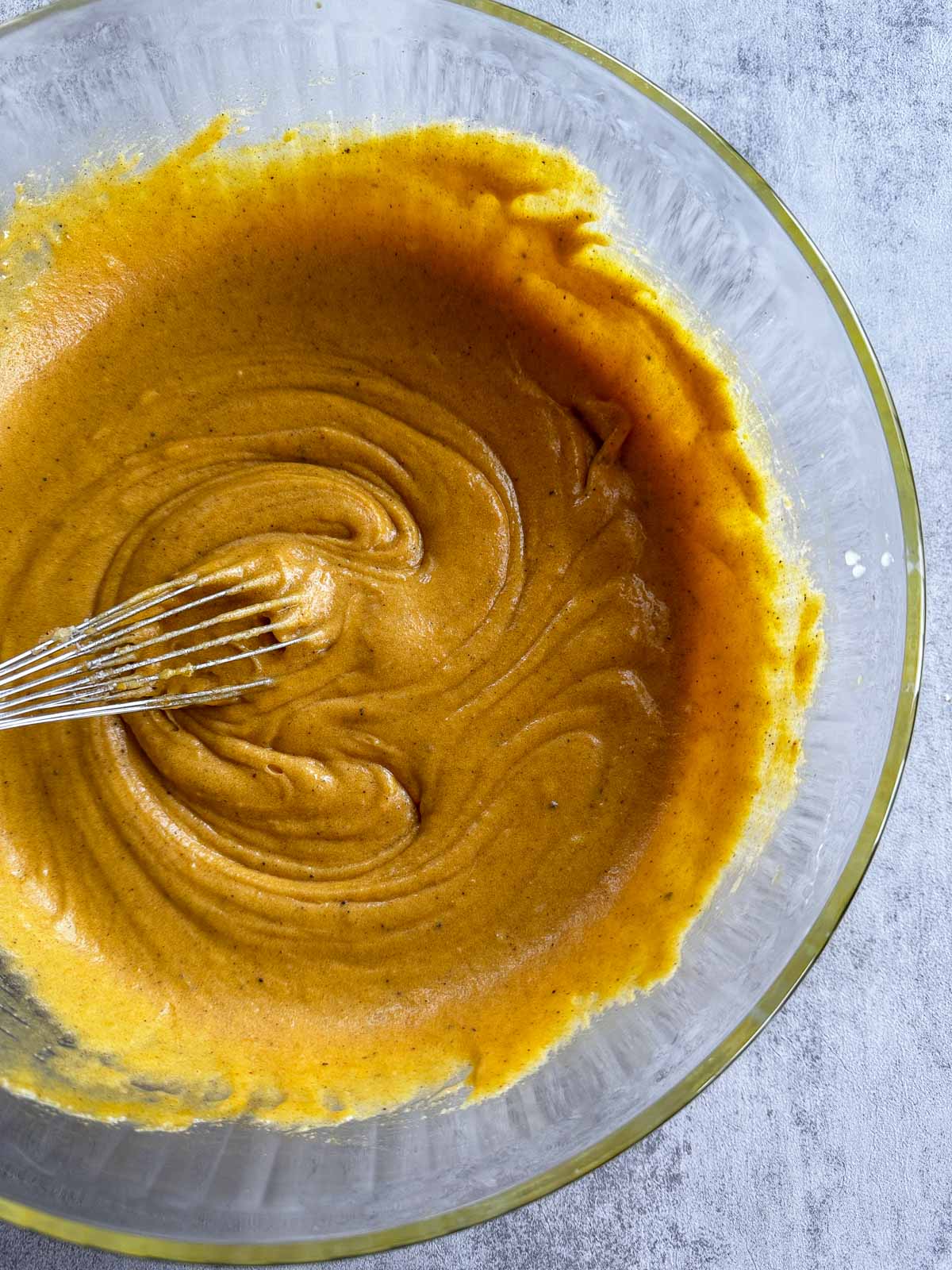 egg yolk and sugar batter being stirred in a glass bowl.