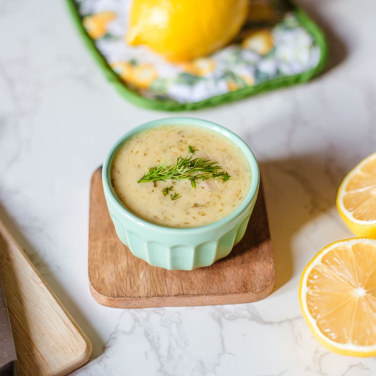 lemon and dill sauce beside herbs, lemon, knife.