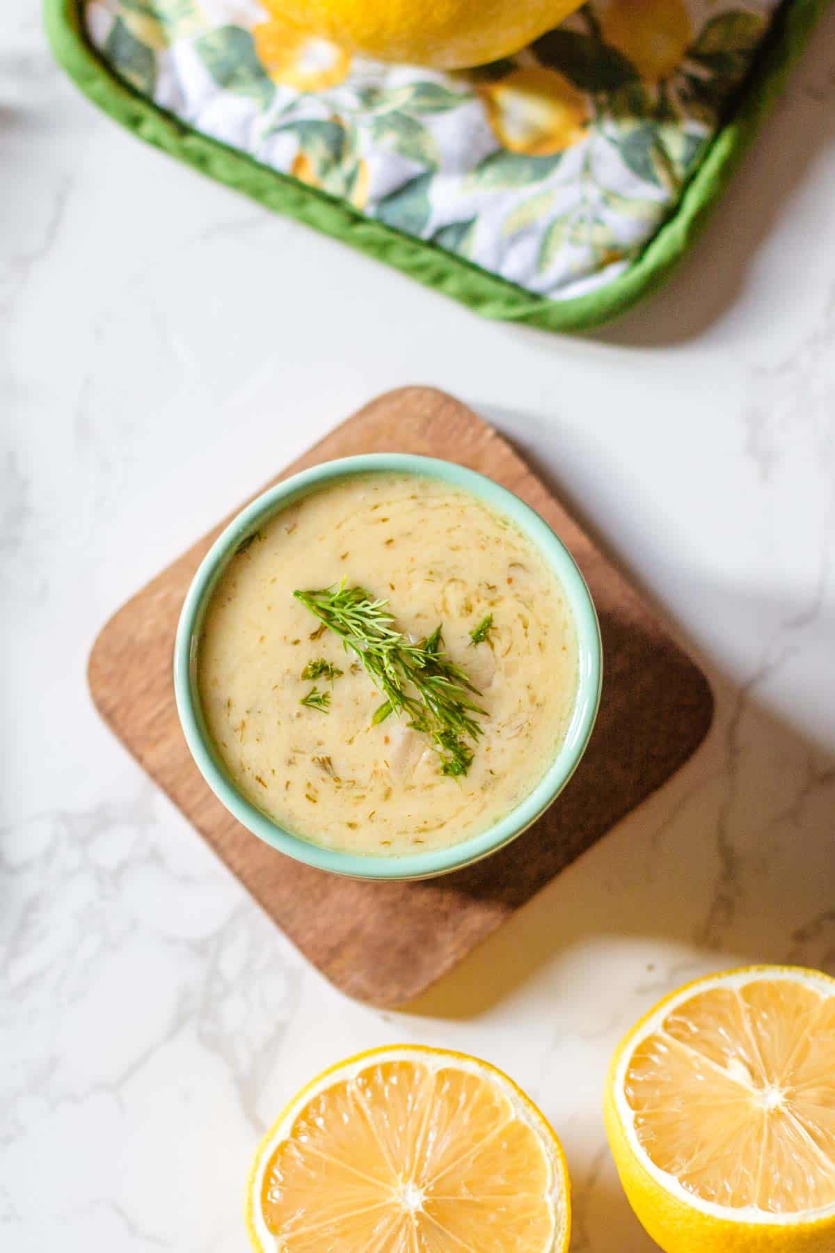 lemon and dill sauce in ramekin beside halved lemons.