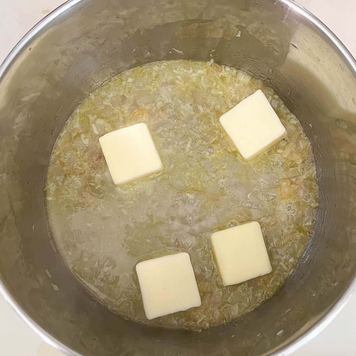 butter slices melting in saucepan amongst shallots.