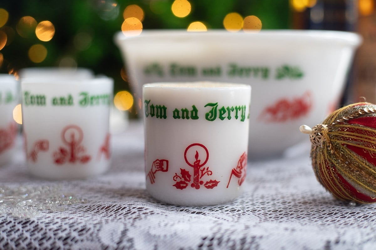 tom and jerry mugs and bowl on a table in front of a christmas tree.