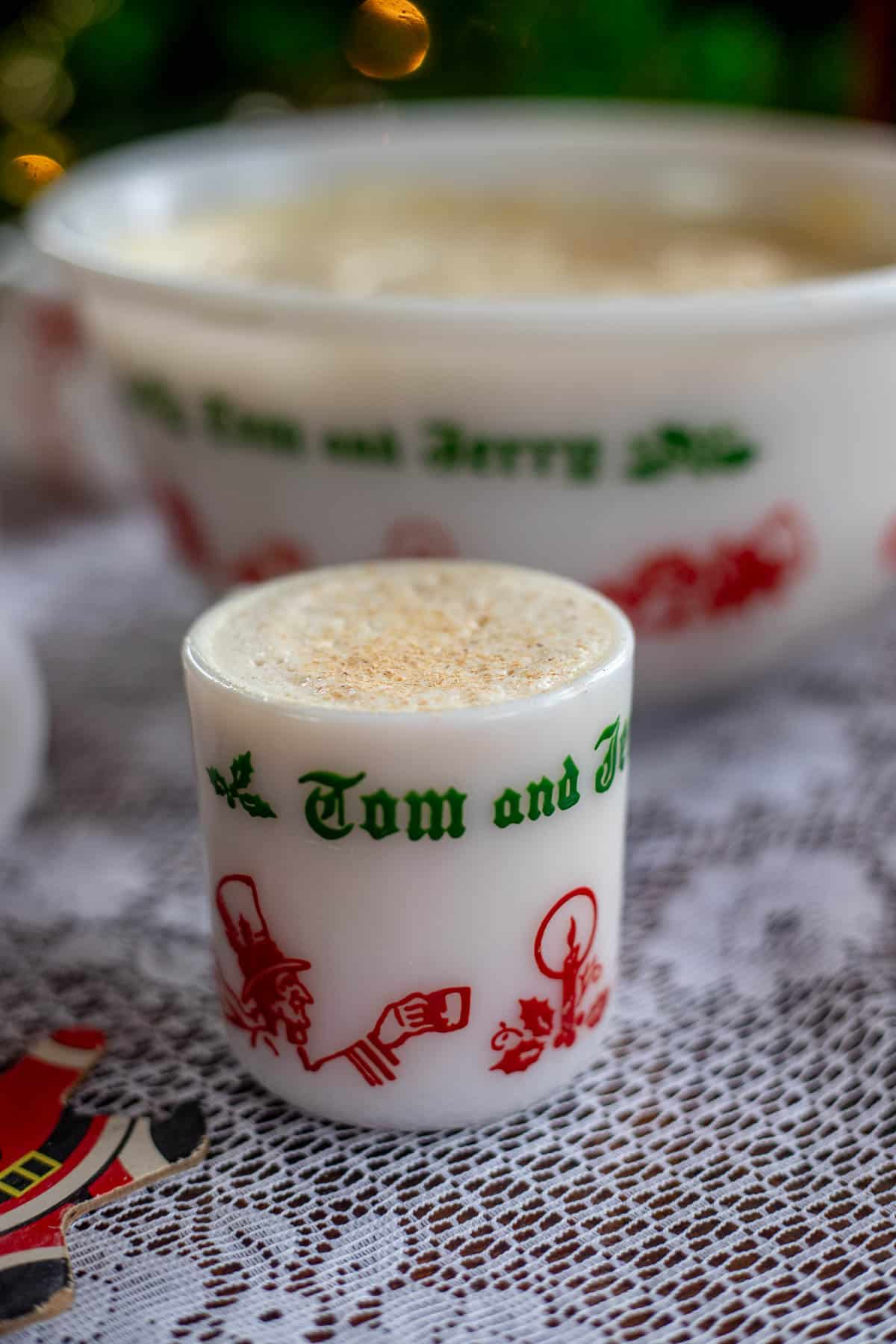 Tom & Jerry batter in a cup and more in a bowl behind it.