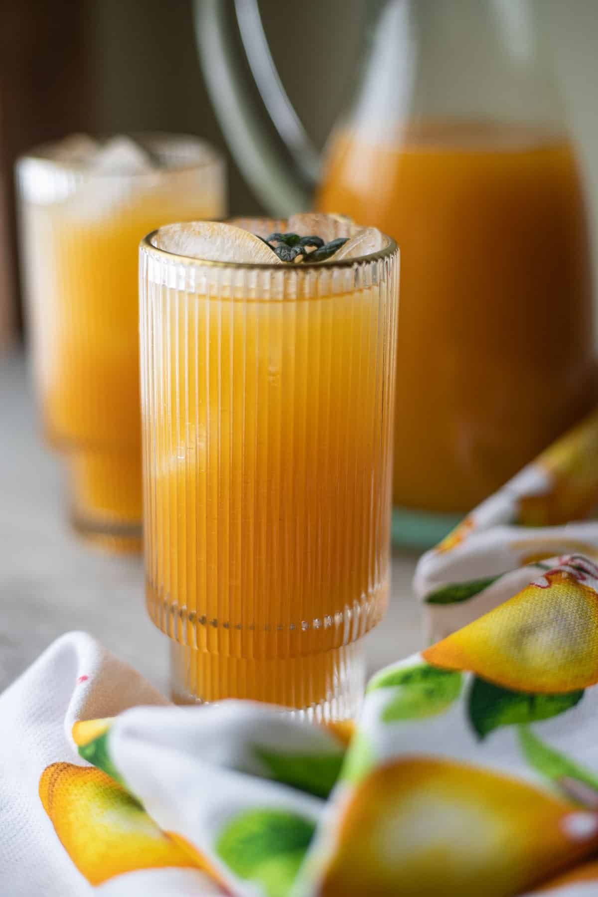 two glasses of apricot nectar with more in a pitcher behind them.