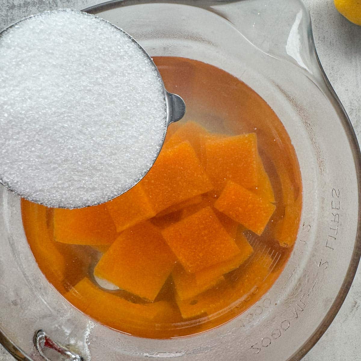 adding suar to a large bowl with cubed apricot paste in water.