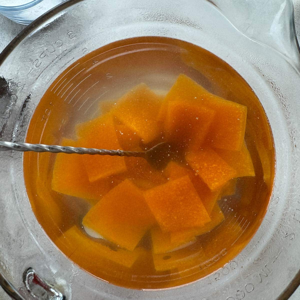 stirring cubed apricot paste in a bowl of water.