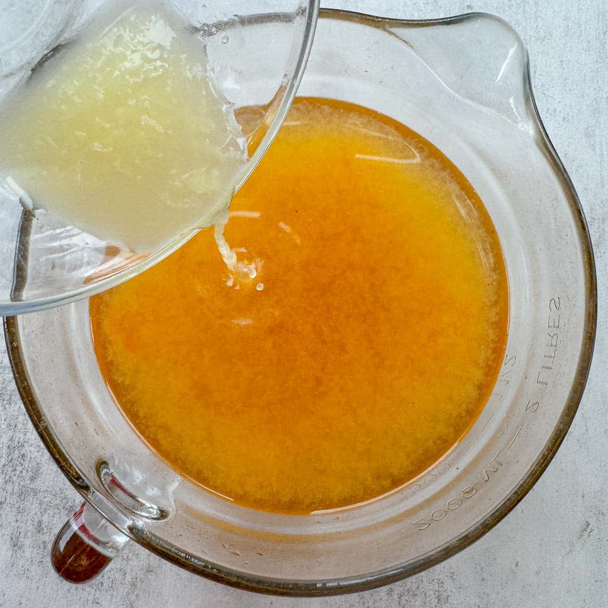 pouring lemon juice into a large measuring cup of qamar al deen.