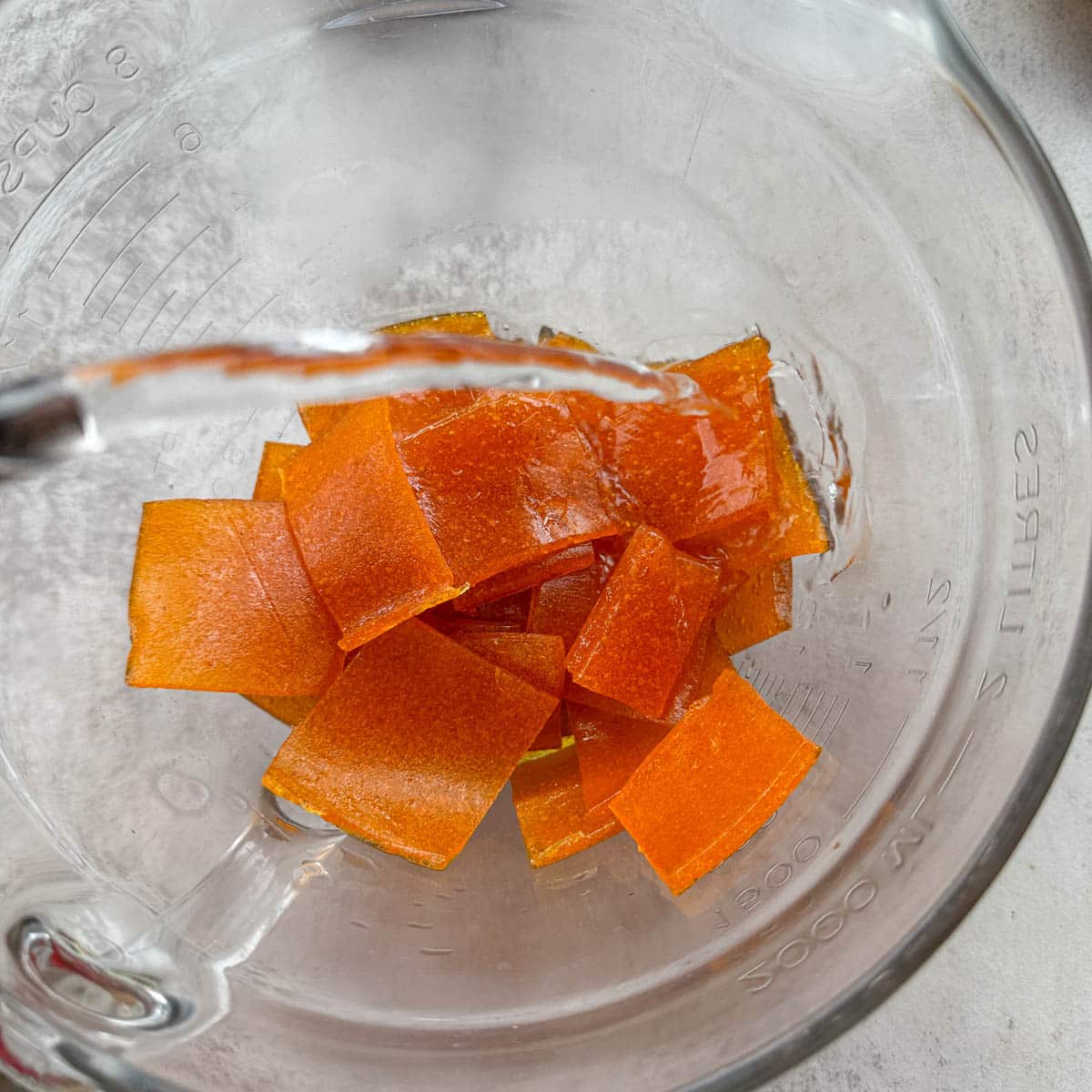 chopped apricot paste in a large bowl with water being added to it.