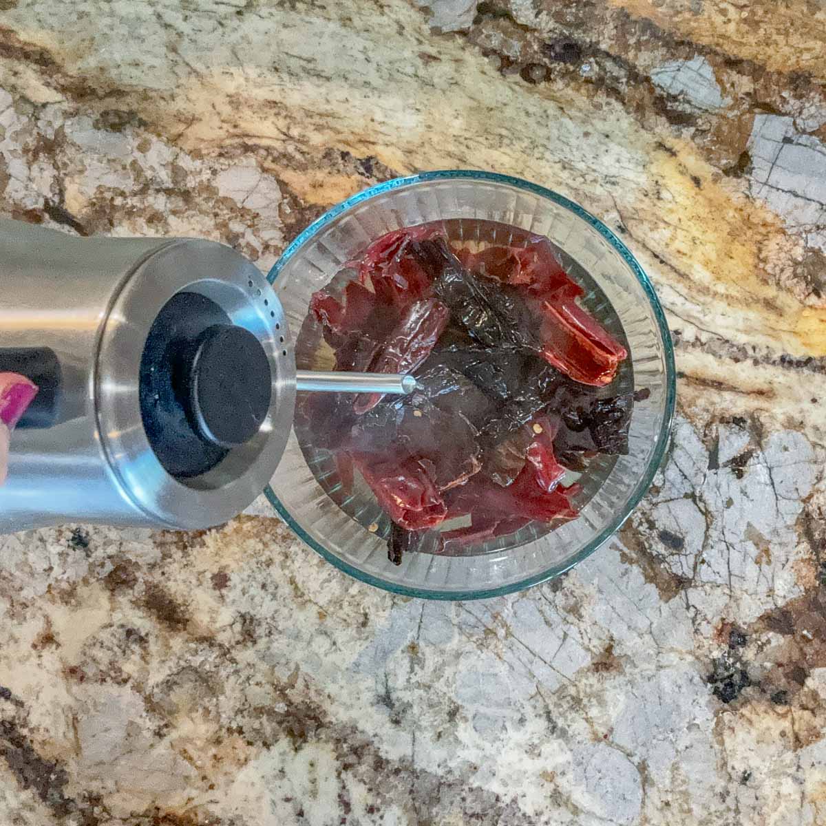 pouring hot water over dried chiles in a bowl.