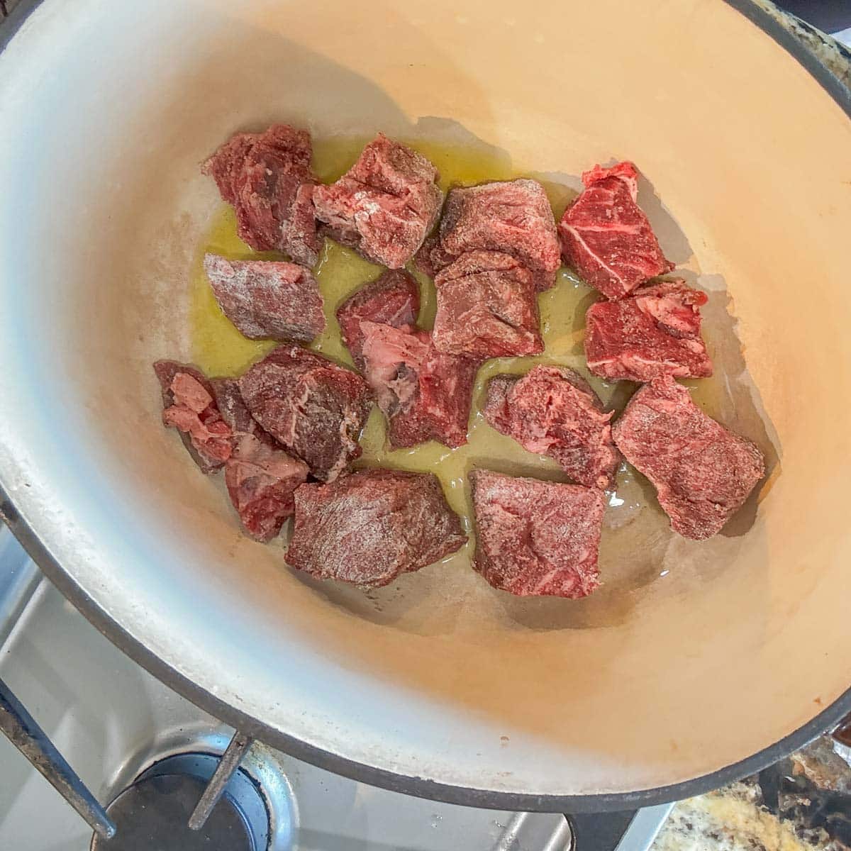 cubed meat frying in a pot. 