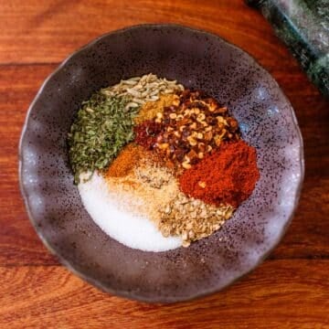 bowl full of harissa substitute spices before mixing (crushed peppers, parsley, salt, paprika, etc.)