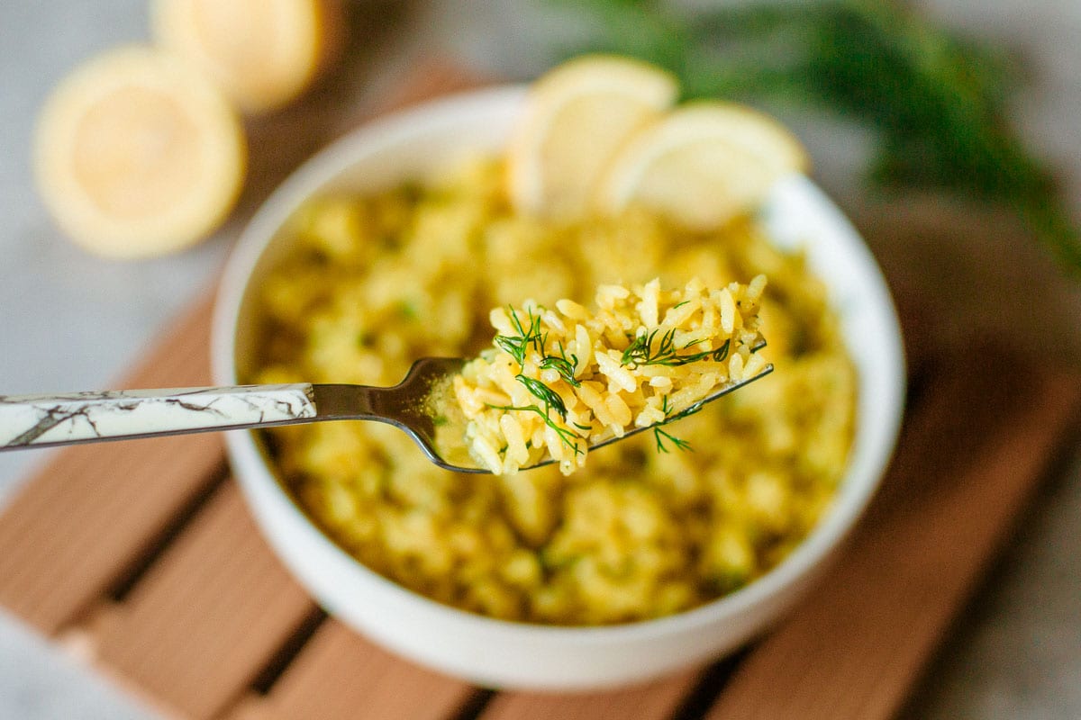 lemon rice full of chopped dill on a fork.