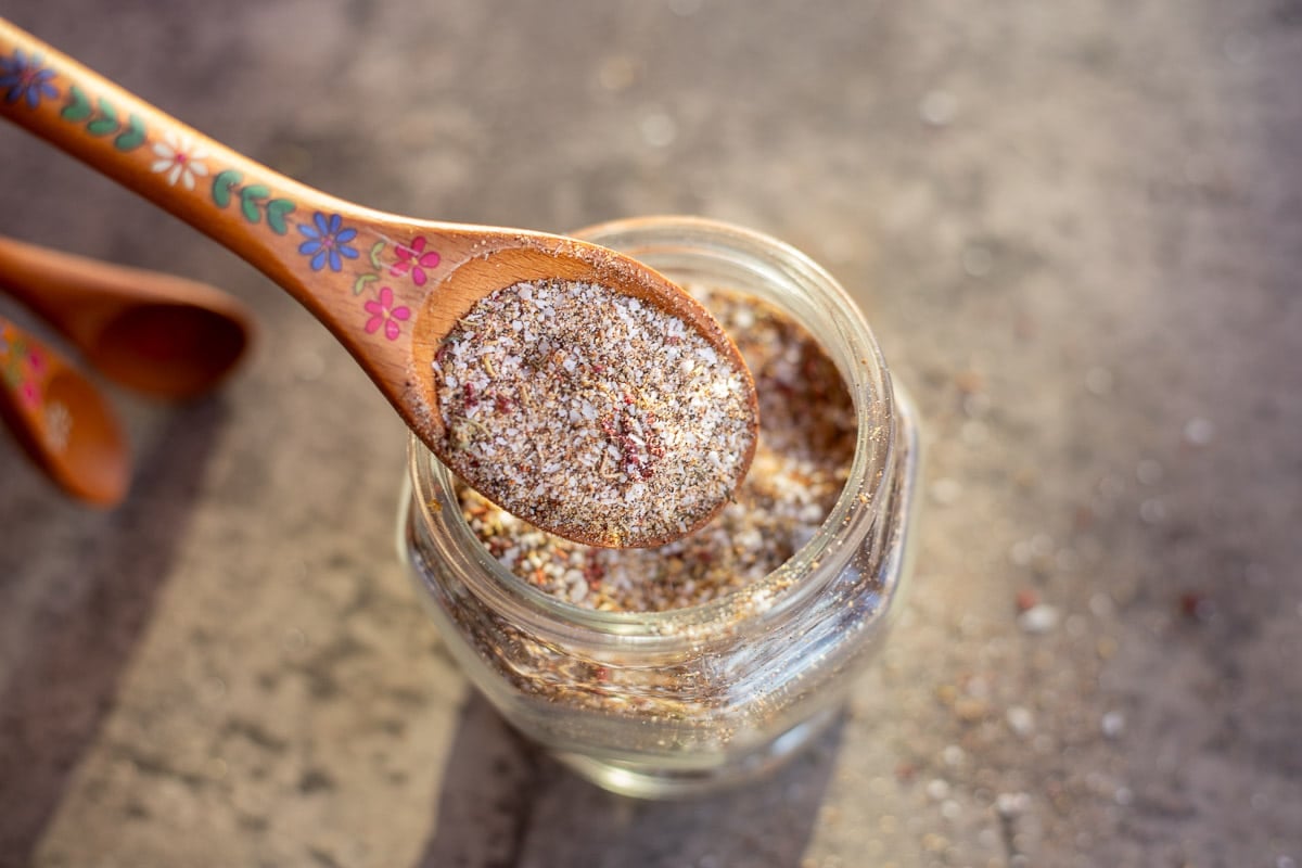 steak seasoning in a jar with more in a wooden spoon.