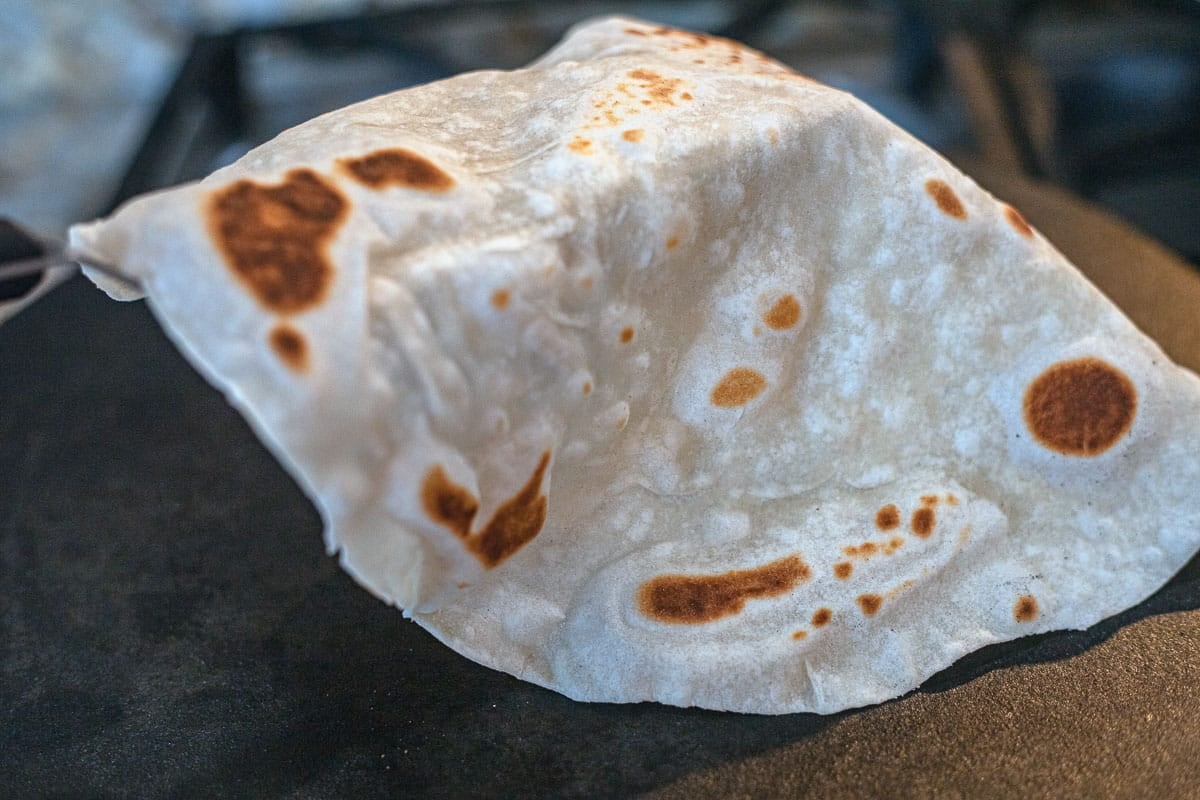 flipping a sourdough discard tortilla on a skillet.