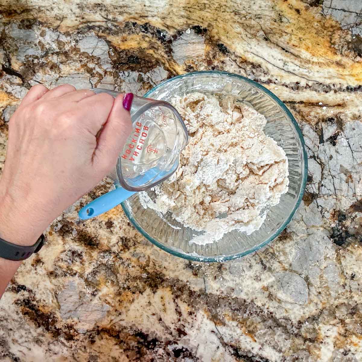 adding water to a bowl of flour mixture. 