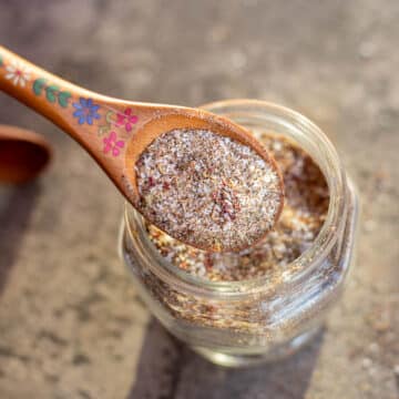 steak seasoning in a wooden spoon over a jar of more steak seasoning.