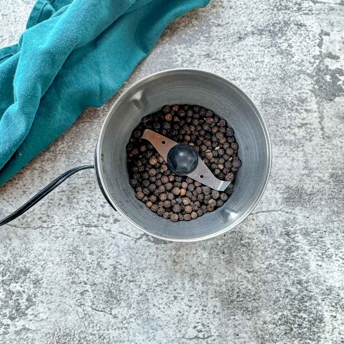 peppercorn in a coffee grinder with a blue napkin.