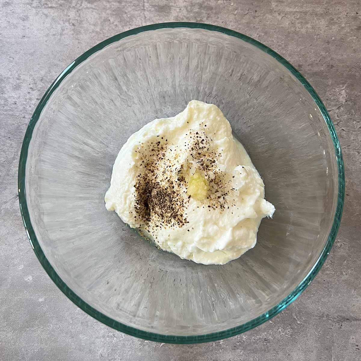 greek yogurt in bowl with garlic and pepper.