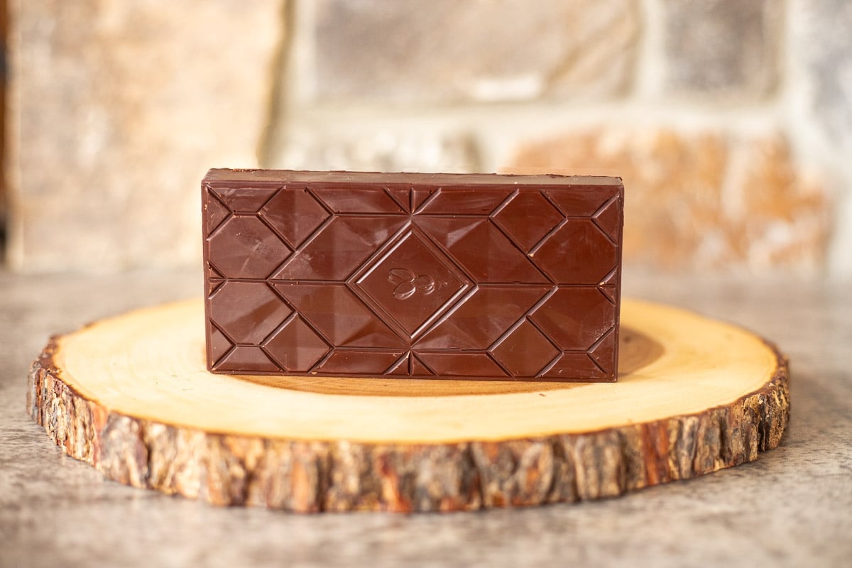 a dubi chocolate bar on its side on a round slice of wood.