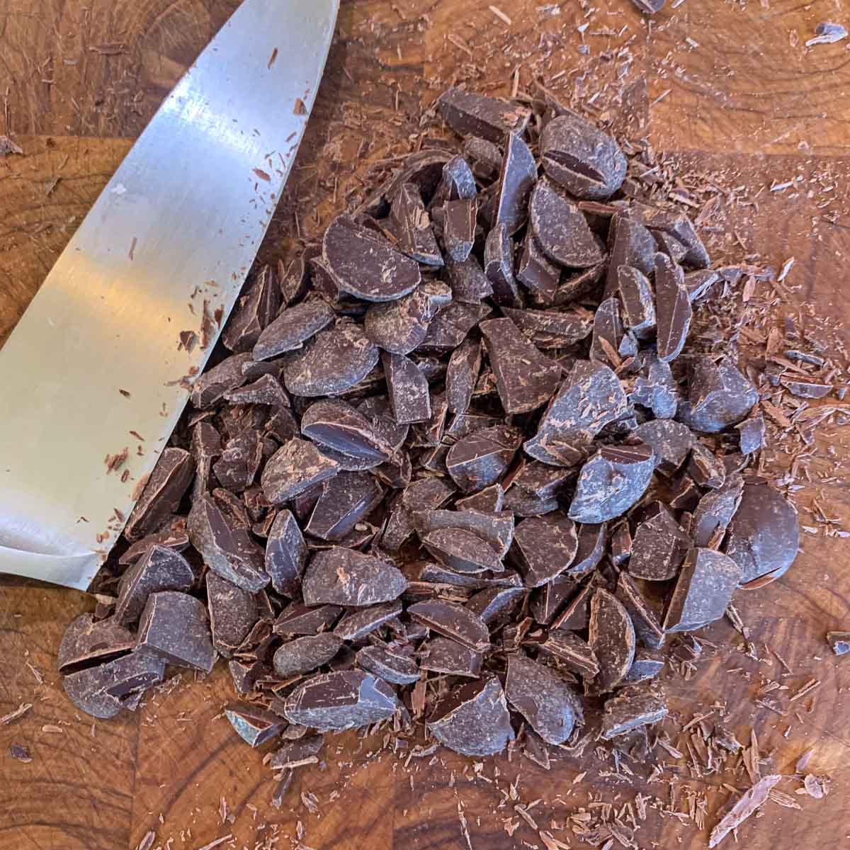 chopped chocolate wafers on a chutting board with a knife next to them.