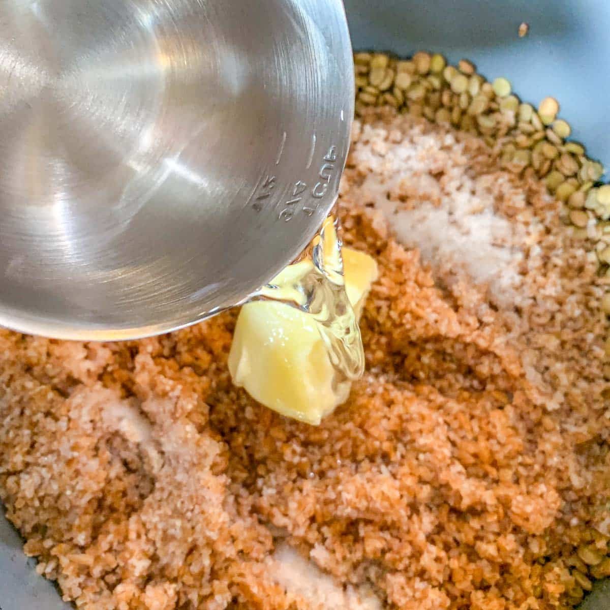 pouring water over a pot of mujadara ingredients. 