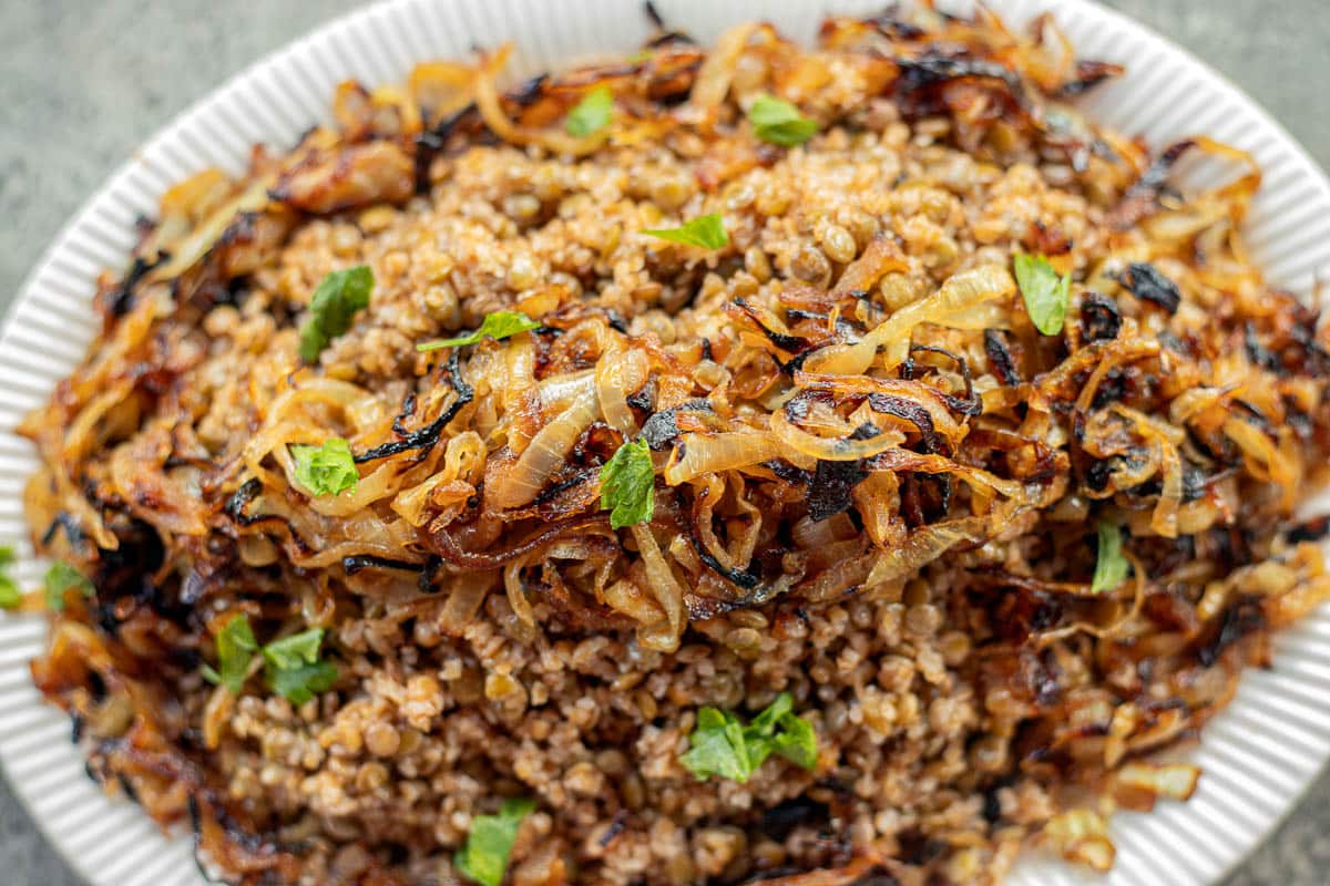 Lebanese mujadara with caramelized onions, garnished with chopped parsley.