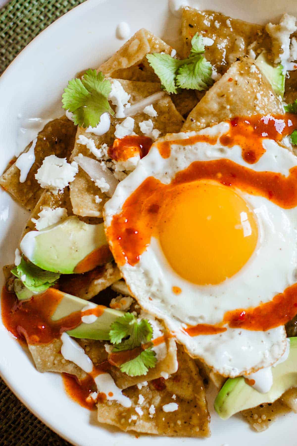 Chilaquiles verdes with a fried egg and hot sauce.