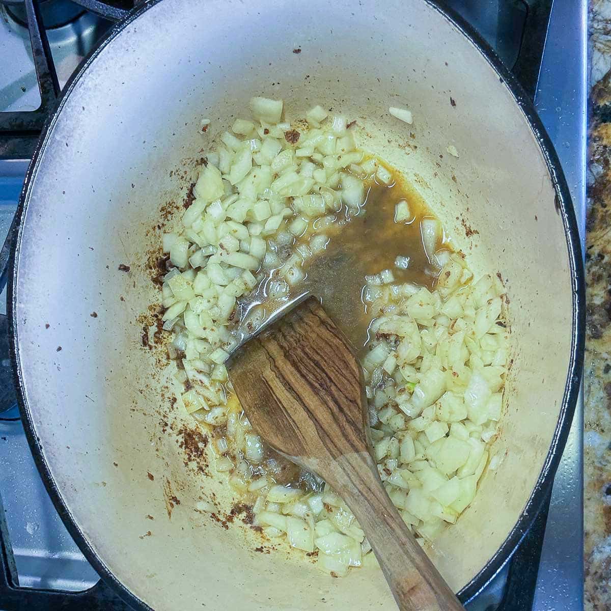 diced onions and a wooden spoon in a pot.