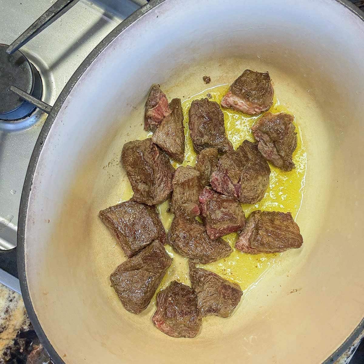 seared cubed meat in a pot.