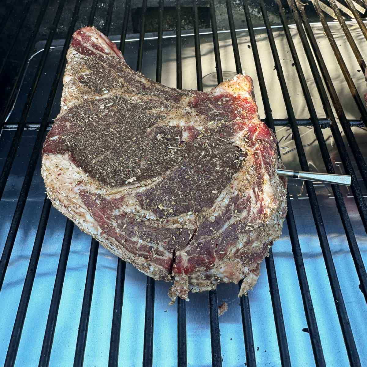 a raw ribeye steak on a smoker grill.
