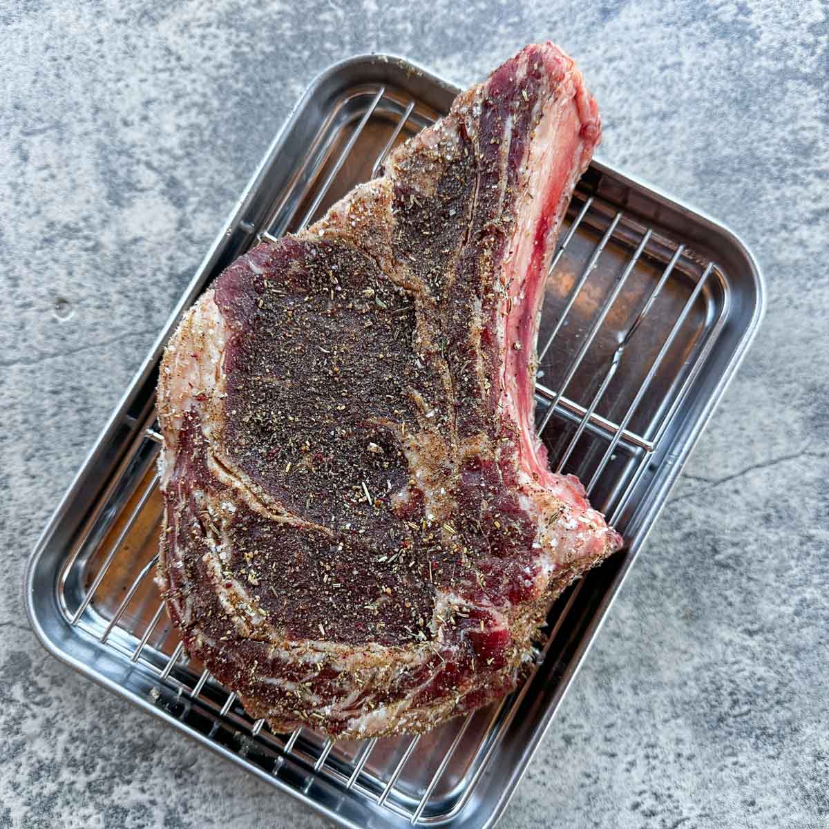 a dry brined steak on a small metal tray.