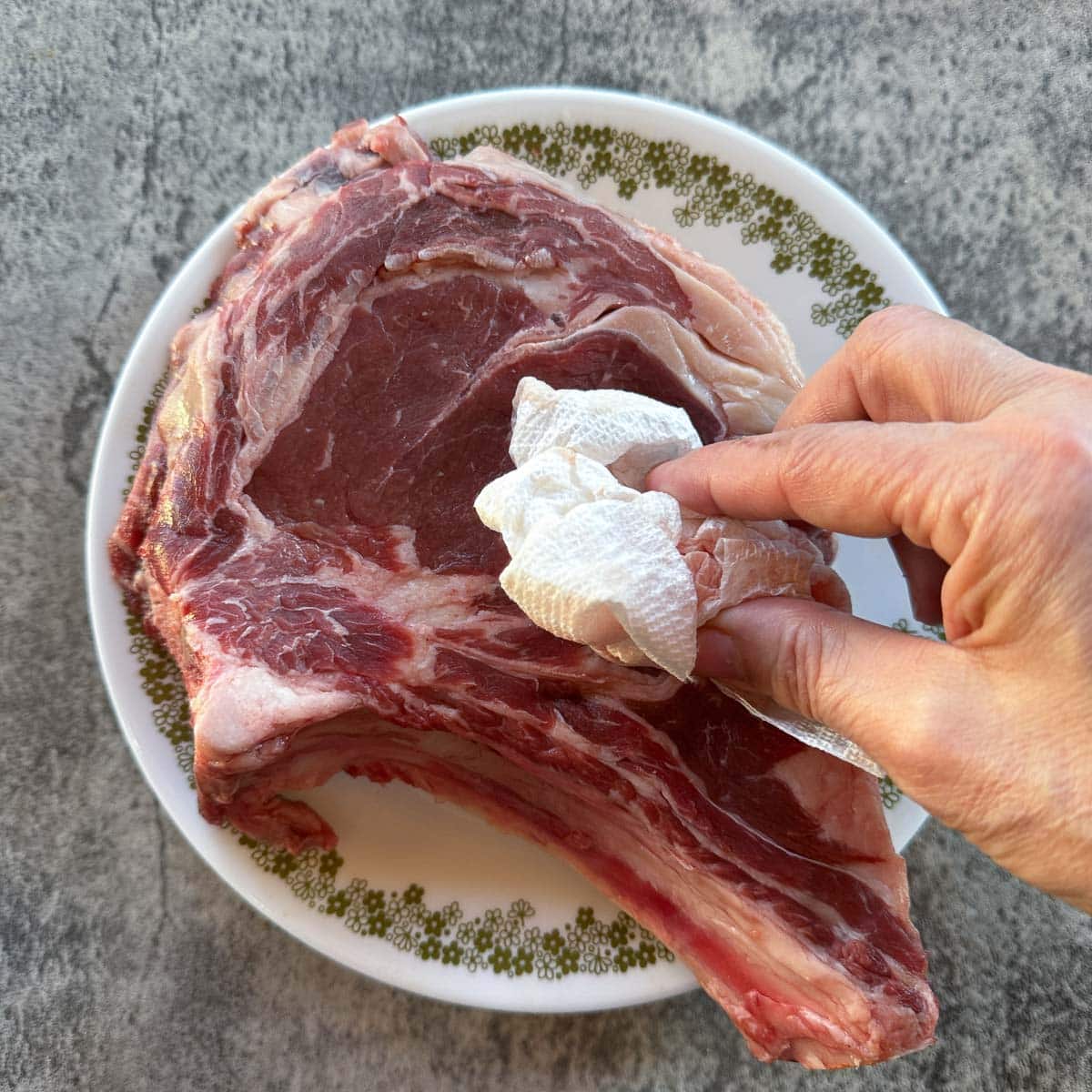 drying a ribeye steak with paper towels.