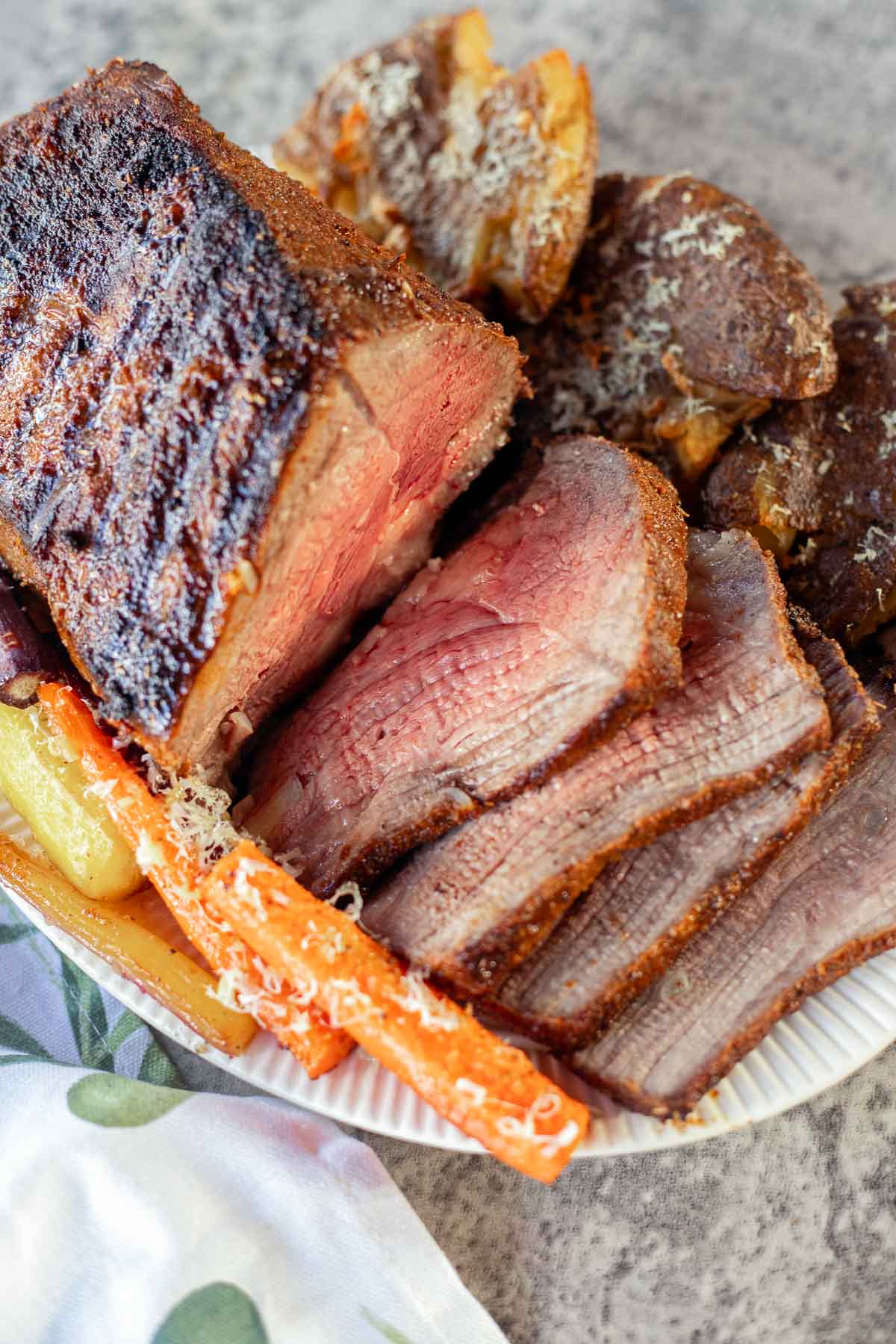 bottom round roast sliced with carrots and potatoes on the side.