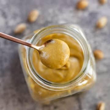 pistachio cream in a jar being spooned out.