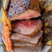 sliced bottom round roast with carrots and potatoes on the side.