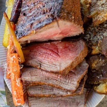 sliced bottom round roast with carrots and potatoes on the side.