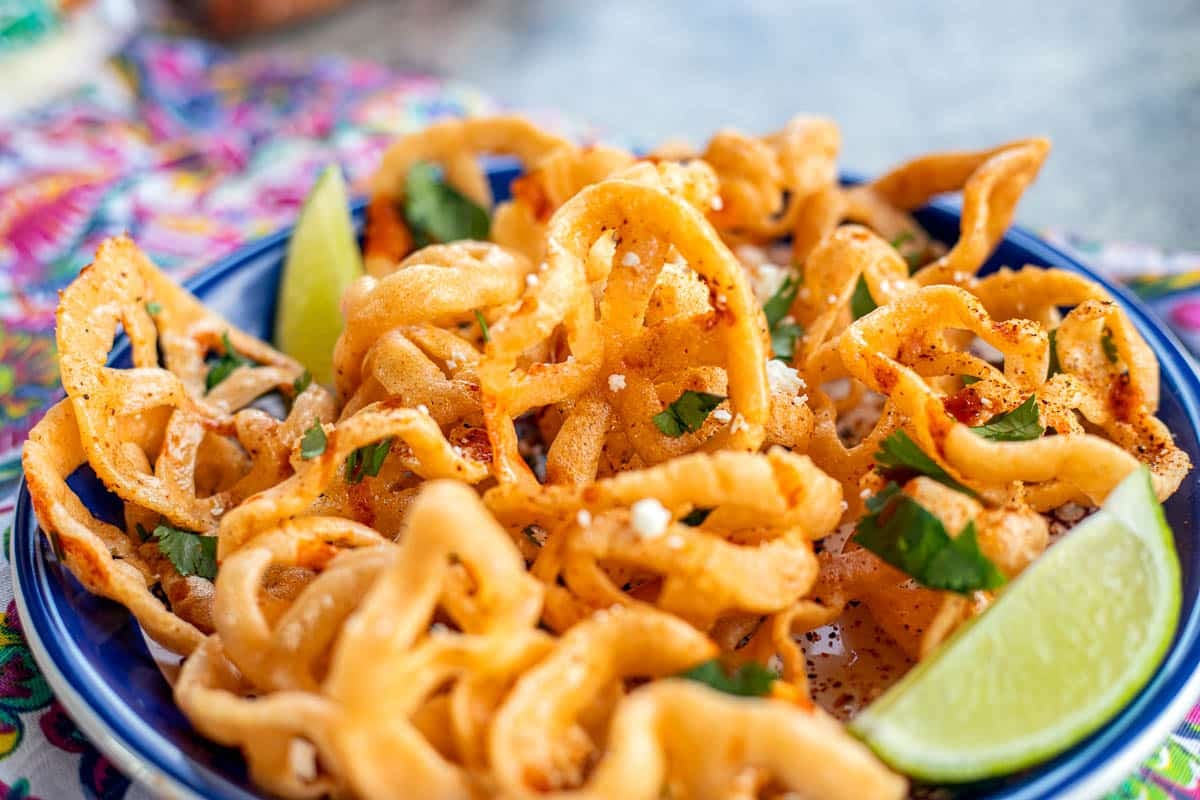 chicharrones de harina on a blue plate with lime wedges.