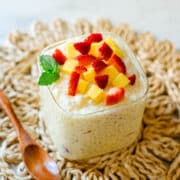 mango sago topped with mango strawberry and mint beside wooden spoon.