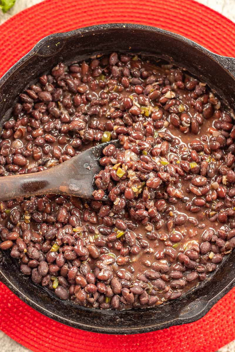 a pan of mexican black beans over a red mat.