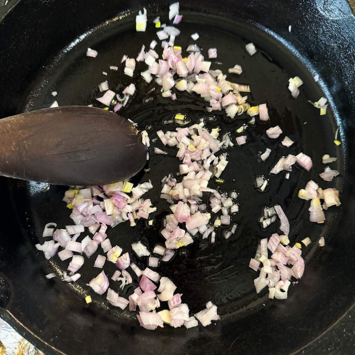 diced shallots being sauteed in a pan. 