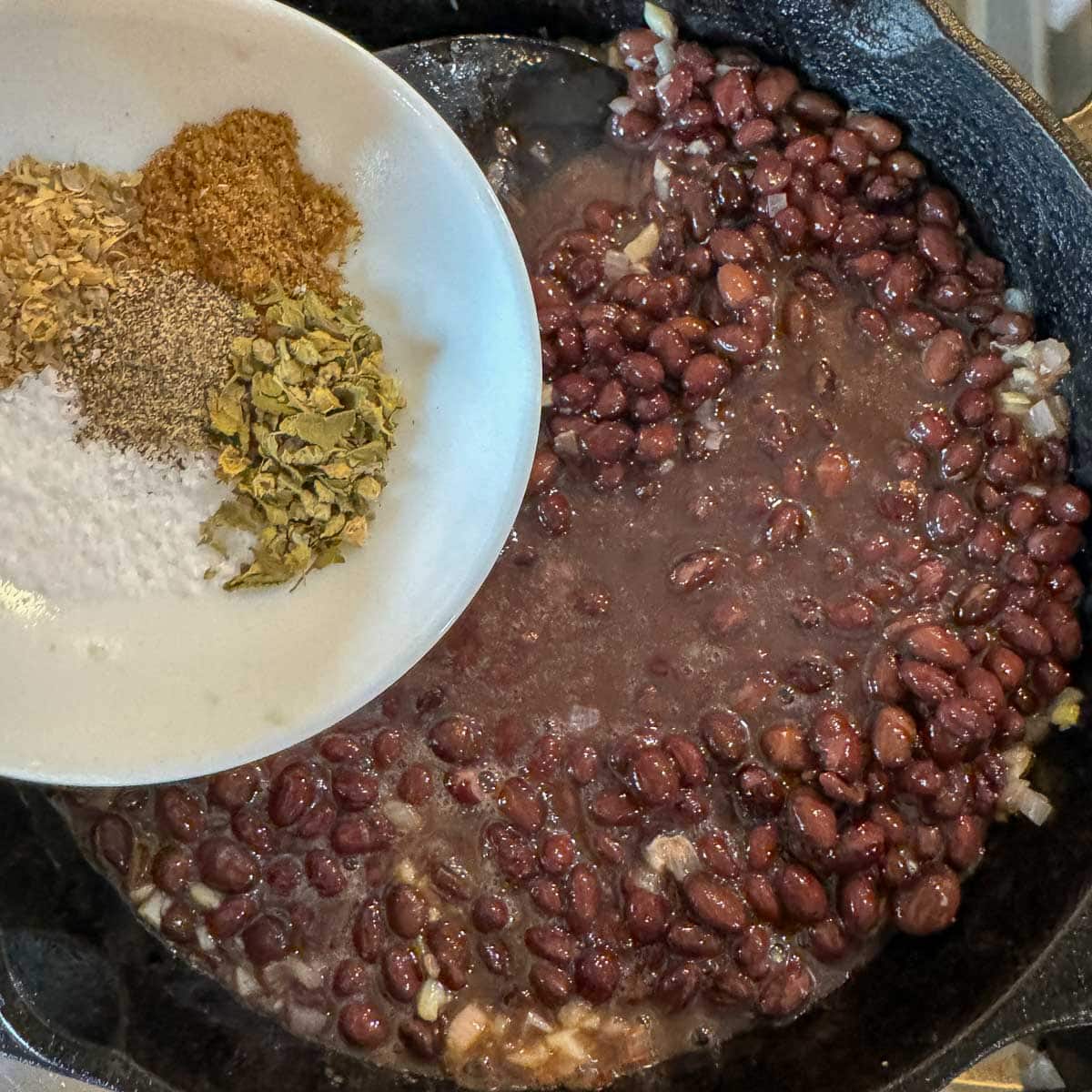 adding seasoning to mexican black beans recipe. 