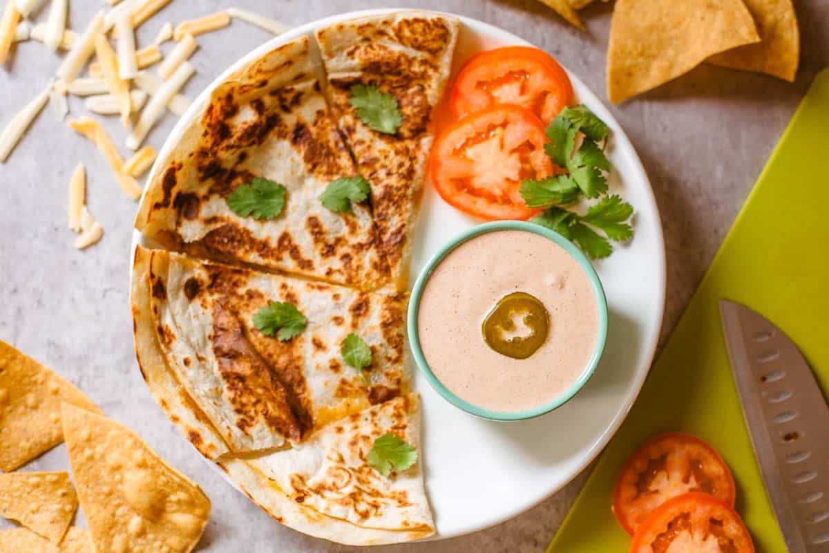 copycat taco bell quesadilla sauce in ramekin beside quesadilla and veggies.
