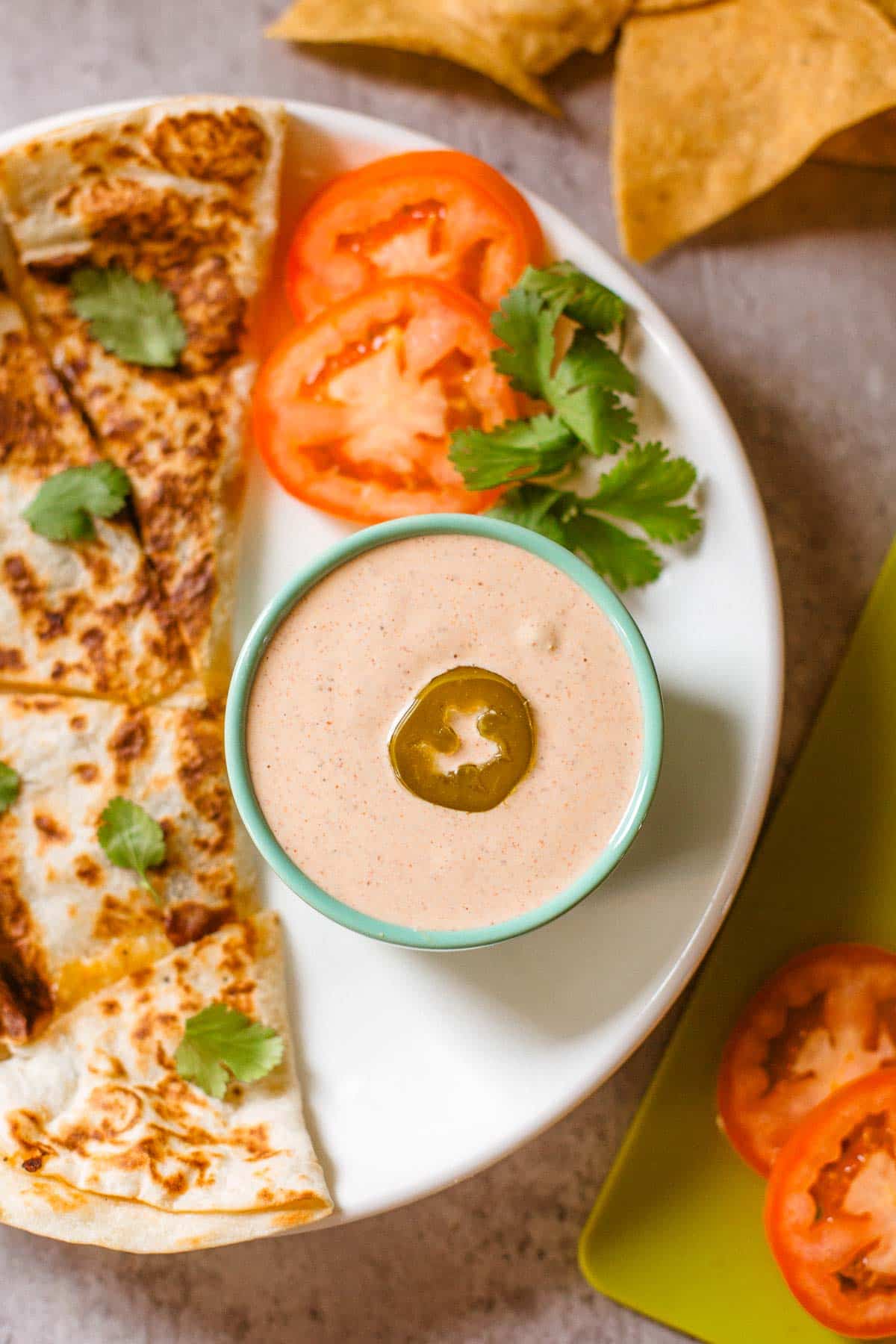 copycat taco bell quesadilla sauce in ramekin beside quesadilla and veggies.