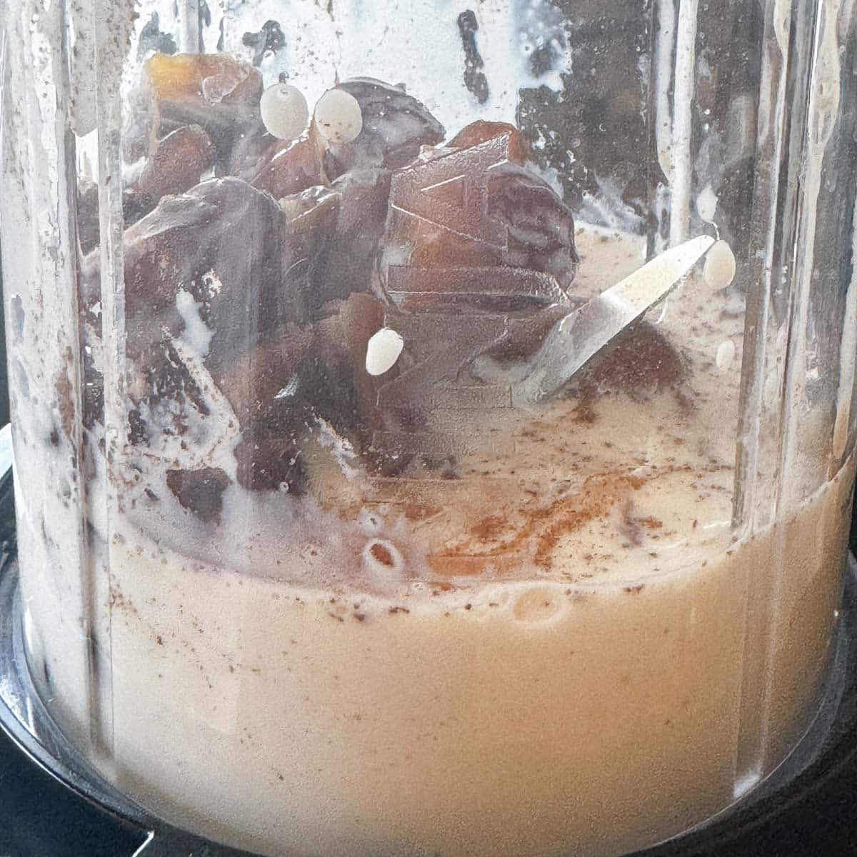 dates, milk, and spices in a shaker cup.