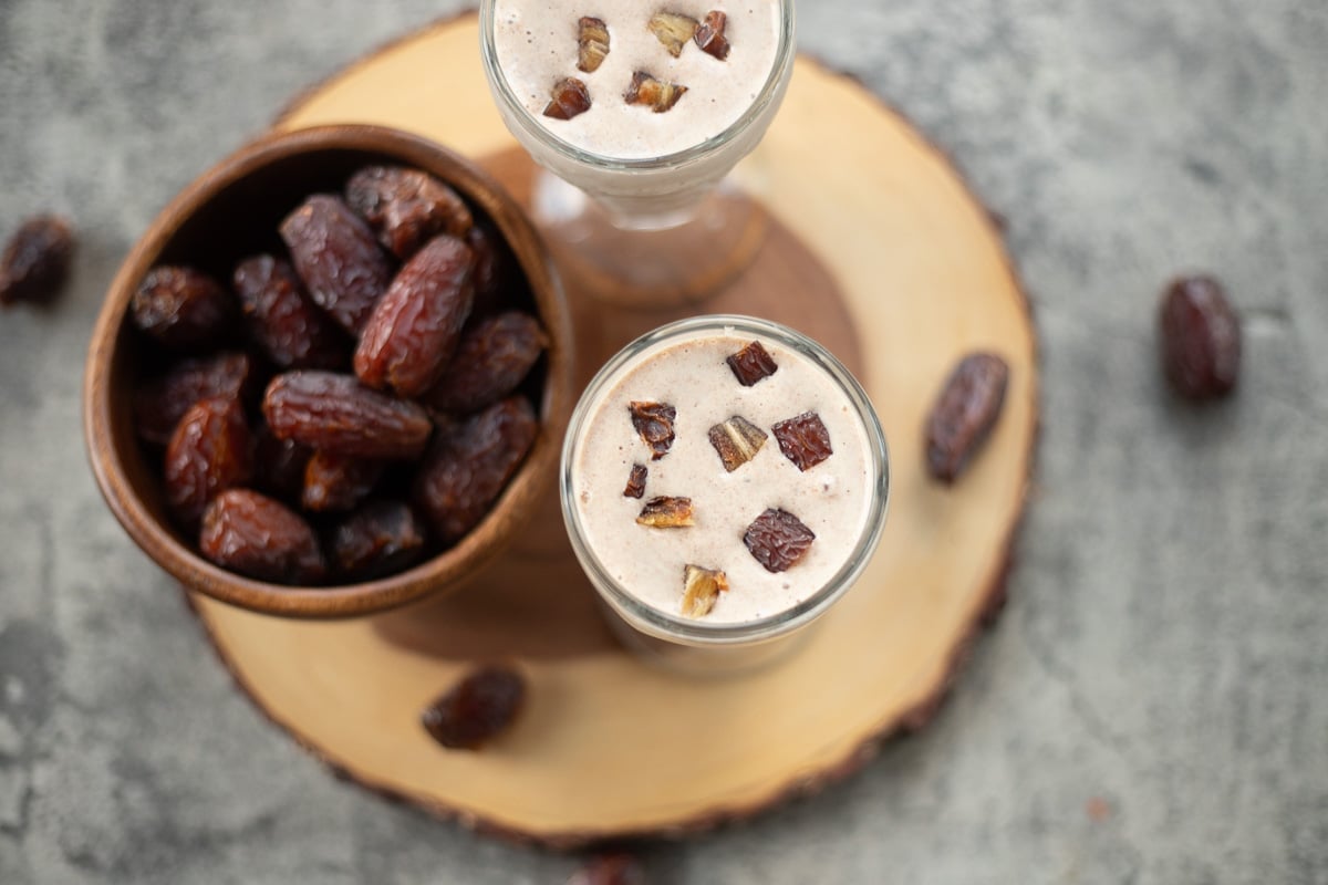 date shakes with a bowl of dates and more dates around the drinks. 