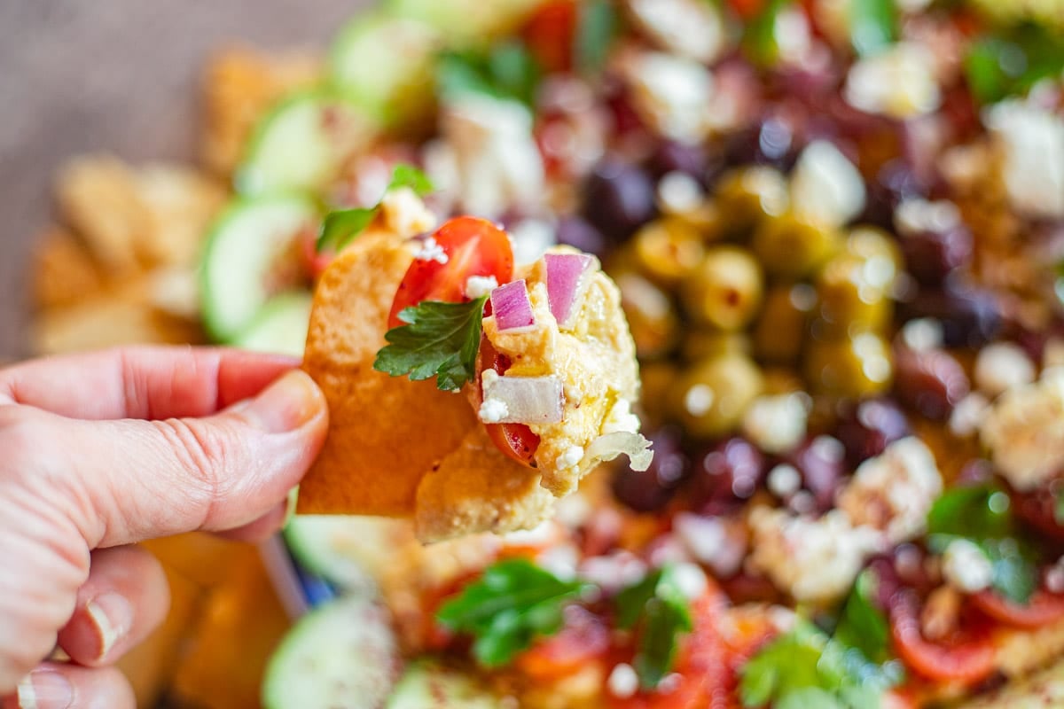 loaded hummus being dipped into with pita chips.