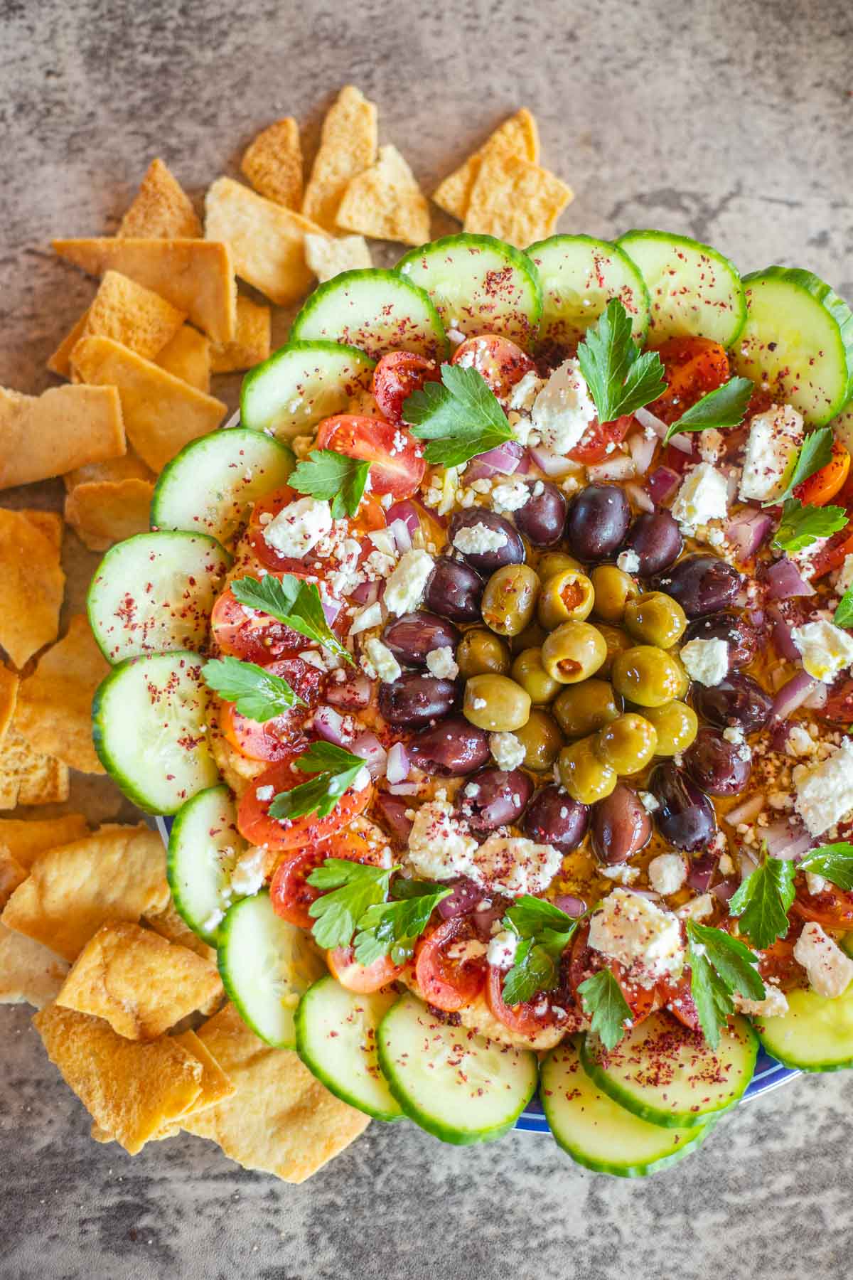 a plate of loaded hummus with pita chips around it.