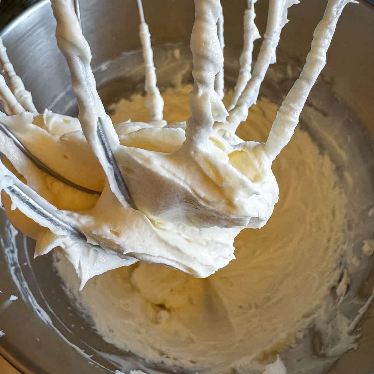 cheesecake batter in a mixing bowl and on the whisk attachment.